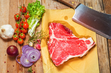 Meat with fresh vegetables, spices and meat cleaver on a wooden