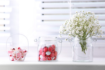 Wall Mural - Sweet candies in jar with flowers on windowsill background