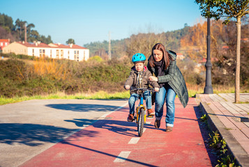 Mother teaching son to ride a bike in cycleway