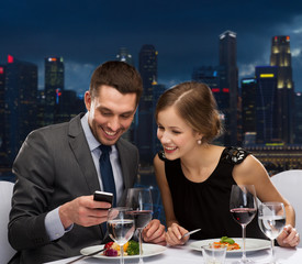 Sticker - smiling couple with smartphone at restaurant