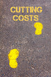 Yellow footsteps on sidewalk towards Cutting costs message