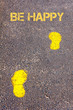 Yellow footsteps on sidewalk towards Be Happy message
