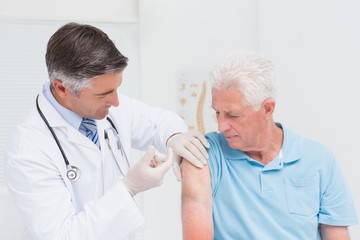 Doctor injecting senior patient in clinic