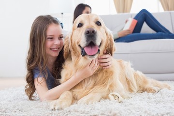 Sticker - Girl embracing Golden Retriever while lying on rug