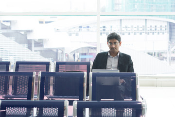 Wall Mural - Asian Indian businessman sitting on chair and using laptop while