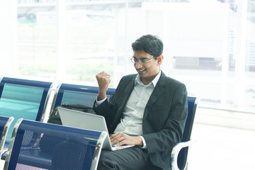 Wall Mural - Asian Indian business man waiting his flight at airport, sitting