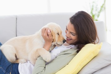 Wall Mural - Woman playing with puppy while lying on sofa