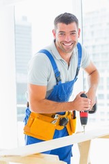 Poster - Happy handyman drilling plank in office