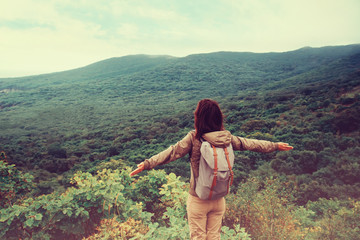 Poster - Traveler girl standing with raised arms on mountain