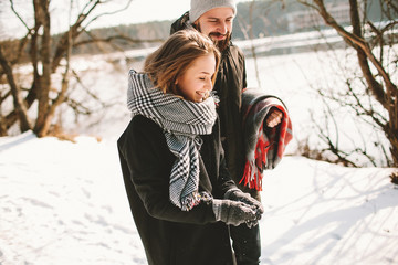 Couple having walk in winter park near frozen lake