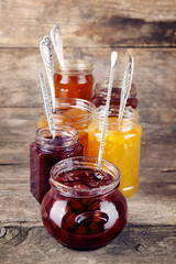 Wall Mural - Jars of tasty jam on wooden background