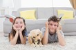 © WavebreakMediaMicro - Happy siblings with puppy lying on rug