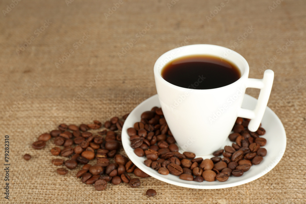 Cup of coffee with beans on rustic wooden background