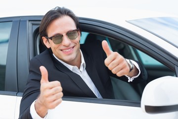 Happy driving businessman with thumbs up