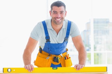 Poster - Smiling handyman using spirit level in office