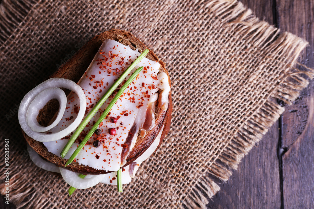 Sandwiches with lard and onion on sackcloth on table close up