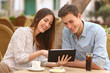 © Antonioguillem - Couple watching media in a tablet in a restaurant
