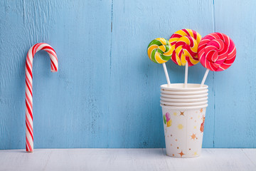 cups and lollipop on the blue wooden background