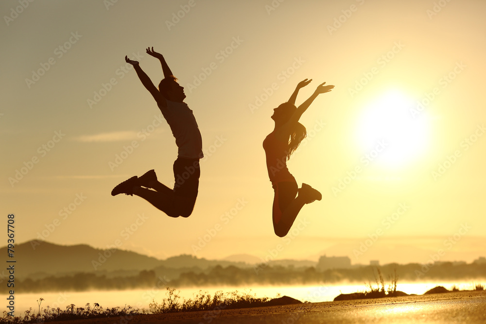 Fitness couple jumping happy at sunset - obrazy, fototapety, plakaty 