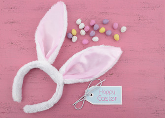 Easter bunny ears on pink wood background.