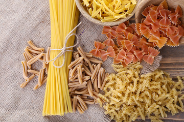 Different types of pasta on sackcloth background