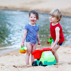 Wall Mural - Little toddler boy and girl playing together with sand toys near