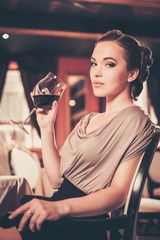 Wall Mural - Young woman with glass of red wine alone in a restaurant