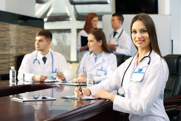 Beautiful young doctor with team in conference room