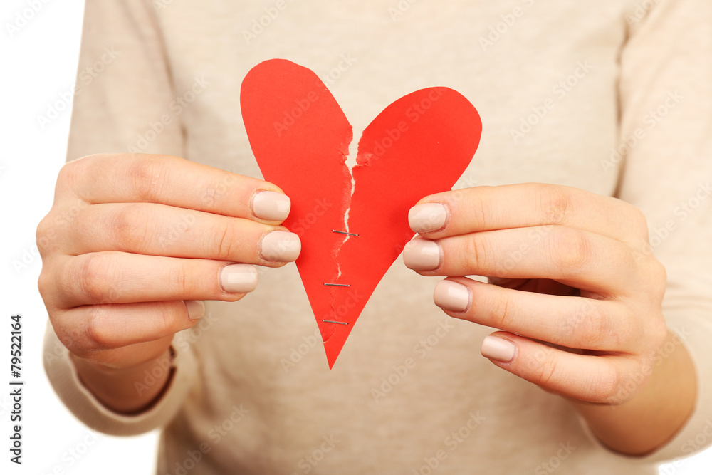 Woman holding broken heart stitched with staples close up