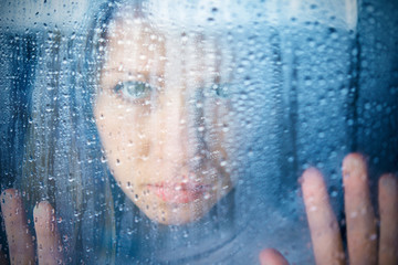 Poster - melancholy and sad young  woman  at the window in the rain