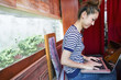 © Mint Images - A woman working on a laptop and sitting indoors.