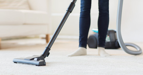 Wall Mural - close up of woman legs with vacuum cleaner at home