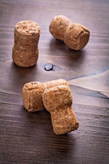 four corks of champagne on vintage wooden board alcohol concept