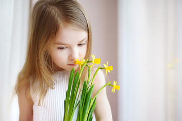 Wall Mural - Adorable girl holding daffodils by the window