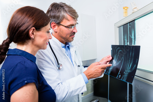 Fotografía Arzt mit Röntgenbild von Hand der Patientin