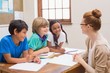 © WavebreakMediaMicro - Teacher and pupils working at desk together