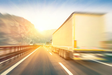 Semi trucks speeding on the highway at sunset