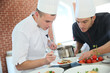 © goodluz - Chef with young cook in kitchen preparing dish
