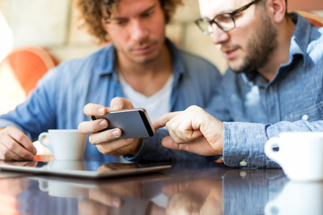 Casual guys in a Coffee Shop looking at mobile phone