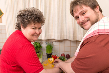 Wall Mural - Geistig behinderte Frau und junger Mann schneiden gemeinsam Gem