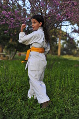 Wall Mural - Young girl in kimono w yellow belt exercising karate.