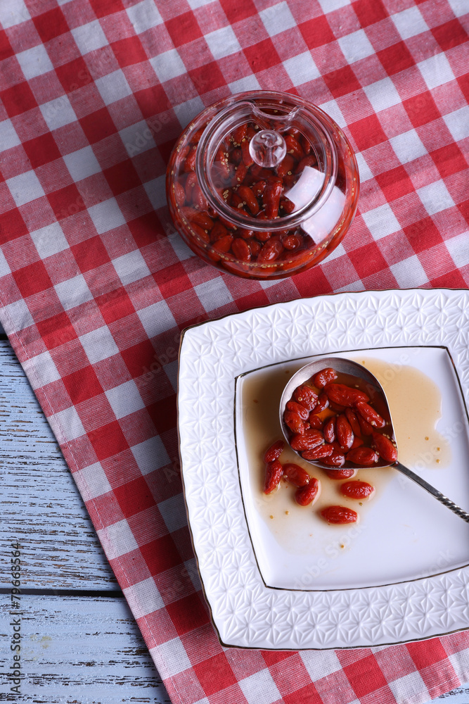 Goji berry jam in spoon on plate with jar on table close up