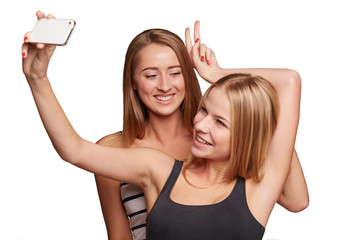 Two girls friends taking selfie with smartphone, isolated on whi