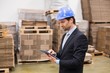 © WavebreakmediaMicro - Warehouse manager wearing hard hat using tablet