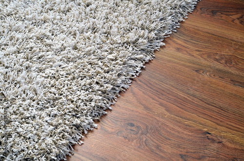 Fotografía Alfombra lanuda blanca en suelo de madera marrón
