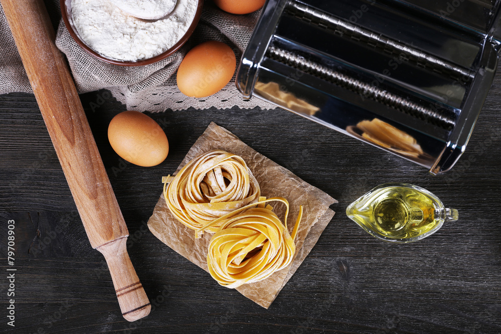 Preparing pasta by pasta machine on rustic wooden background