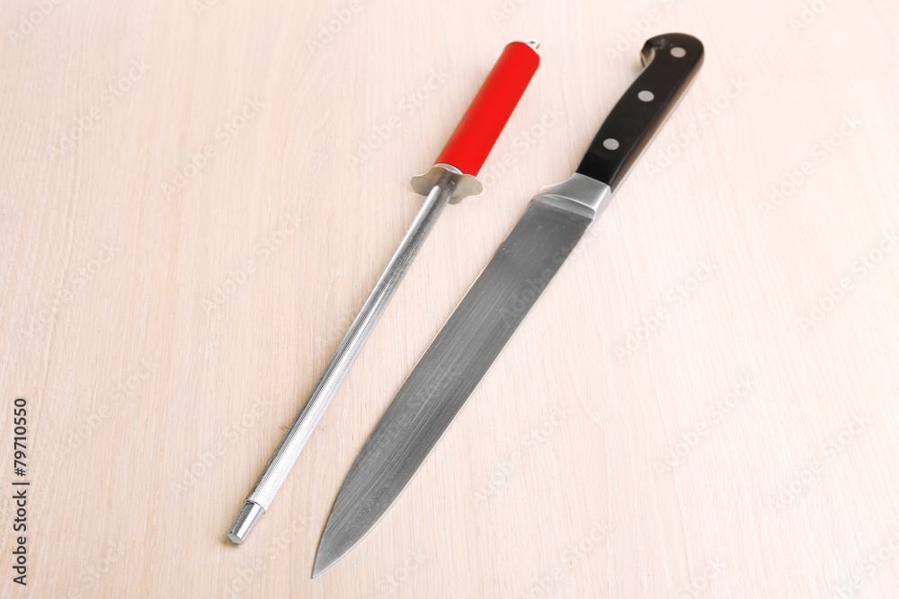 Knife with sharpener on wooden background