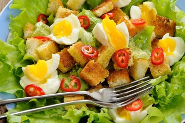 Salad Caesar with eggs, chili pepper and two forks closeup