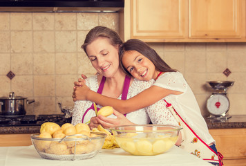 happy, smiling mother daughter cooking dinner preparing food