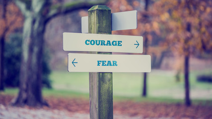 rustic wooden sign in an autumn park with the words courage - fe
